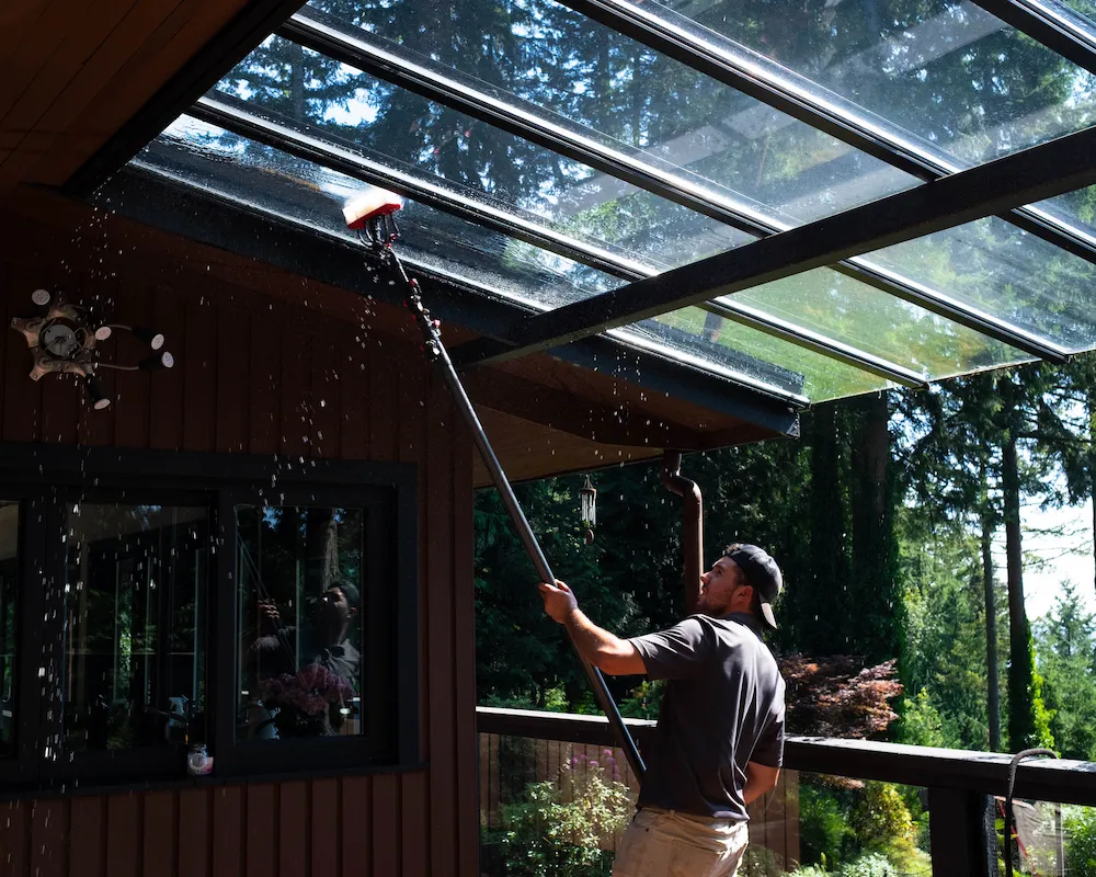 A WashTech technician rinsing overhead glass with a water-fed pole